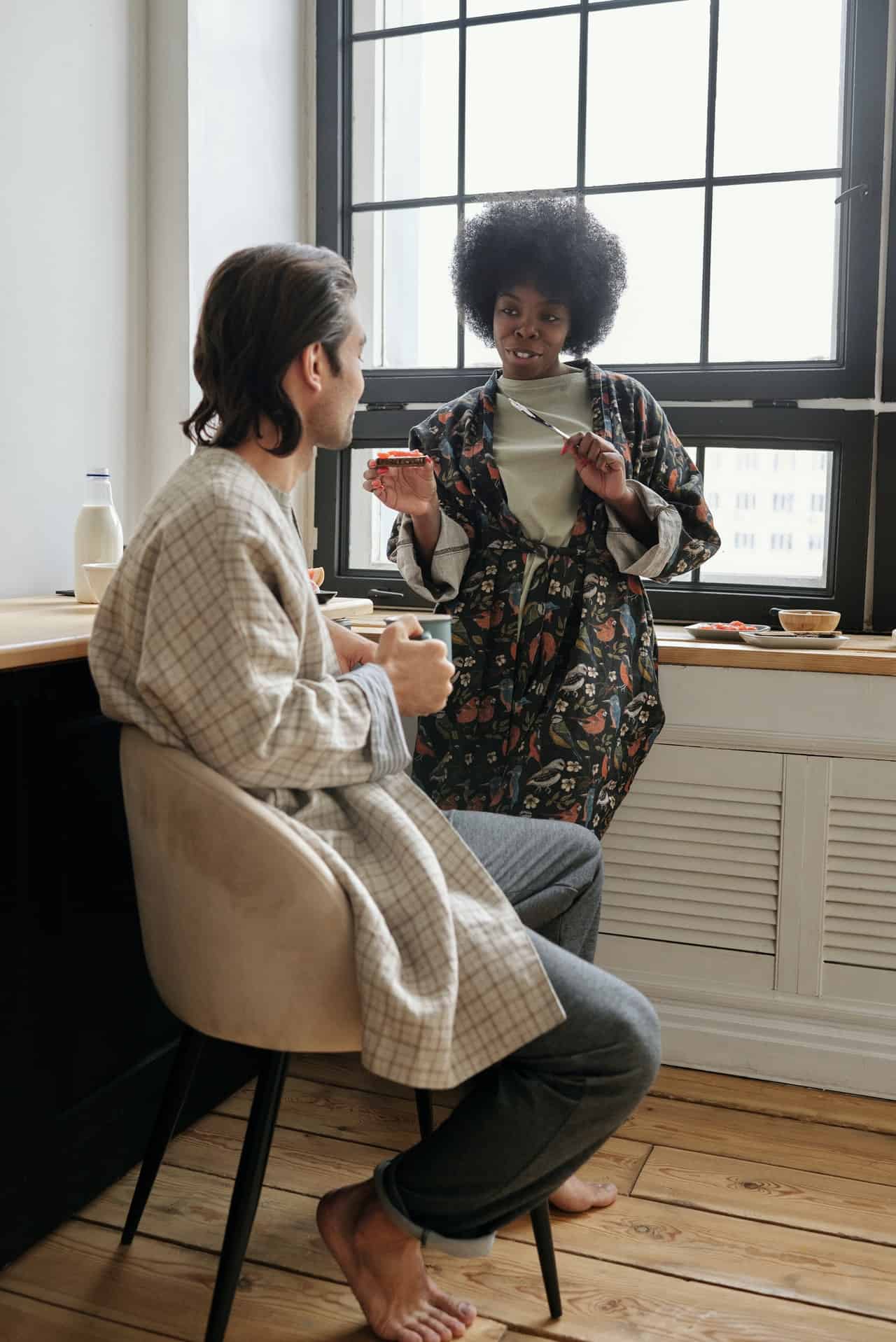 Photo of a multicultural couple having breakfast together and talking in their kitchen. This represents how couples can solve their cross-cultural discrepancies with the help of a therapist specialized in multicultural issues in NC and VA.