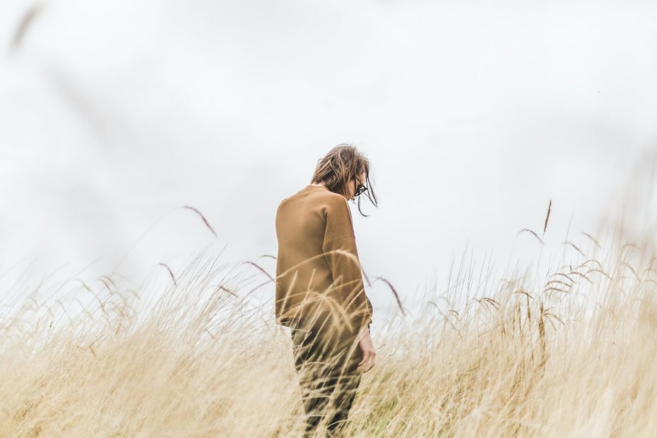 Photo of a person walking alone in a field with a sad expression. This represents how, no matter the struggles you are facing, you don't have to do it alone. Our therapists at Deep Connections Counseling are here to help, so you don't have to feel alone in your journey.