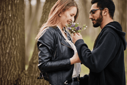 Photo of a man giving flowers to his girlfriend. This represents how pre-marital counseling in North Carolina and Virginia can help you build the foundation for a healthy and happy relationship.