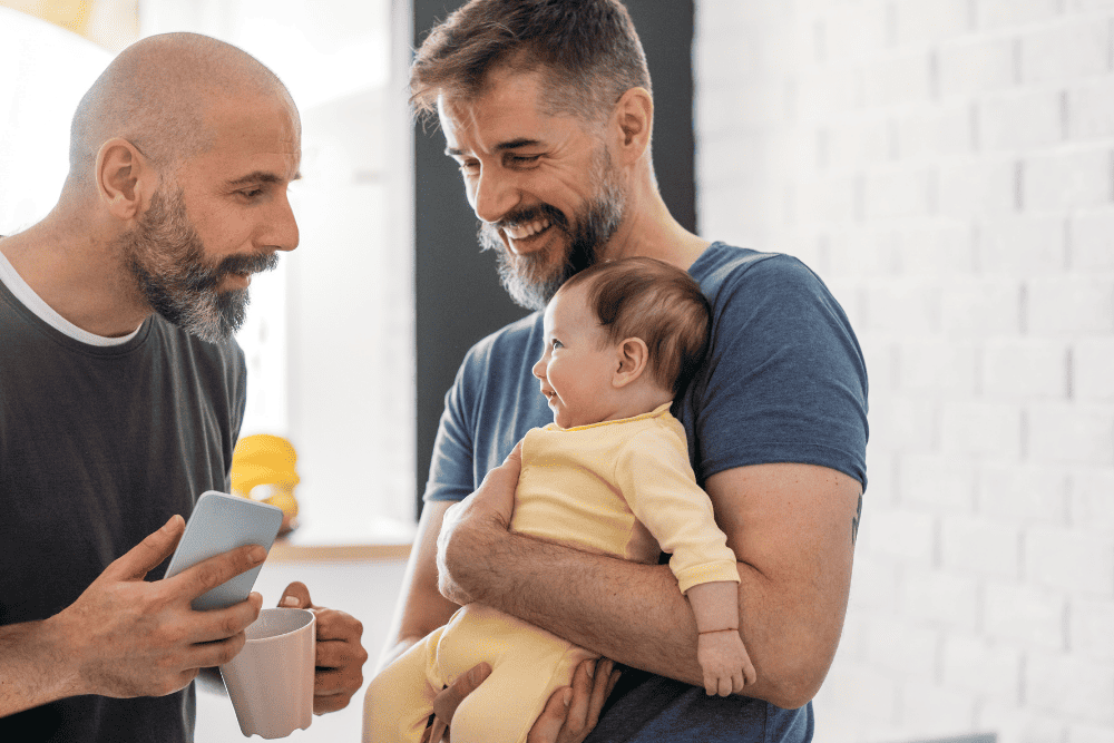 Photo of a gay couple holding their baby. This represents how family counseling can help explore new strategies to help you build your confidence and connect with your loved ones.