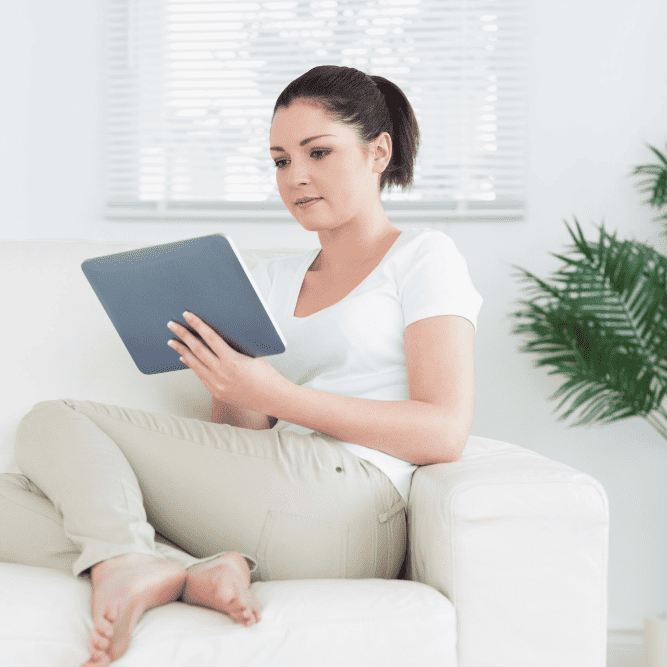 Photo of a woman sitting on the couch with a tablet in her hand looking for a therapist at North Carolina or Virginia. Start online therapy at Deep Connections Counseling and get the support you need.