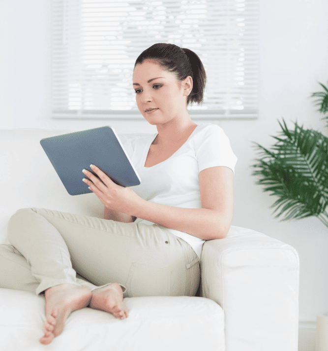 Photo of a woman sitting on the couch with a tablet in her hand looking for a therapist at North Carolina or Virginia. Start online therapy at Deep Connections Counseling and get the support you need.