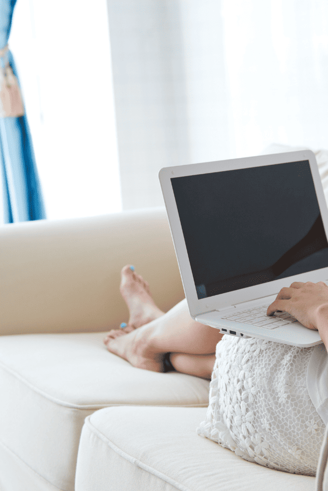 Photo of a woman sitting on her couch with a laptop on her lap, after a therapy session. This represents how online therapy is a comfortable and safe way to get support to overcome your issues.