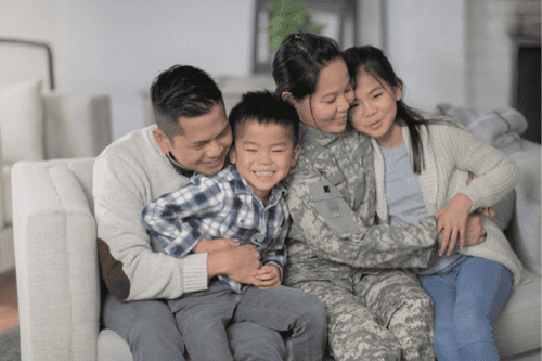 Photo of a military woman hugging her family in a therapy session. This represents how counseling can help families overcome the unique challenges of military life.