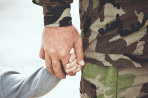 Photo of kid holding the hand of a military man. This represents how military therapy can help you navigate the everyday concerns, improve the relationship with your family, instill healthier coping mechanisms, pick up efficient stress and anger management skills, and learn how to properly adjust after deployment.