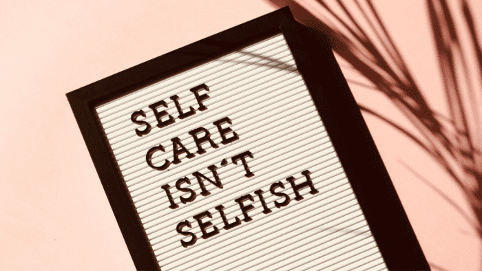 Photo of a screen with the words "Self care isn't selfish". This represents how focusing in your well-being and overcoming the stigma around mental health is a way to change your life by embracing self-care.