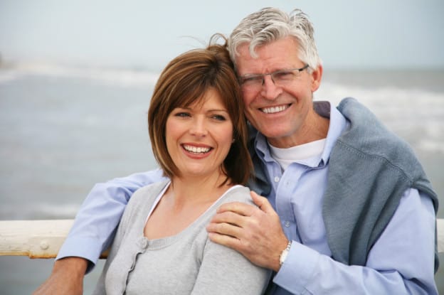 Photo of an older couple holding each other and smiling. Couple Therapy For Empty Nesters And Couples In Midlife Crises provides tools, guidance, and encouragement for couples looking to reconnect and revive their relationship.