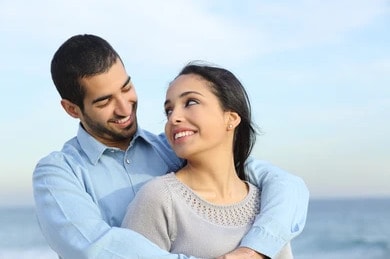 Photo of a couple looking at each other and smiling. This represents how therapy can help you and your partner move forward and feel happier together.