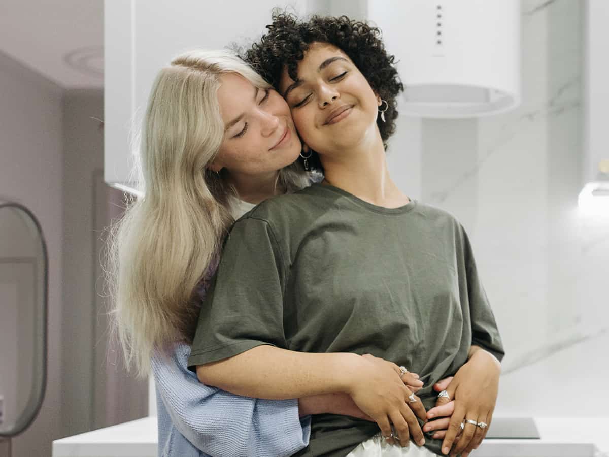 Photo of an LGBTQ+ couple hugging each other with a loving and calm expression. This represents how couples therapy can help rebuild trust in a relationship after a betrayal or infidelity.